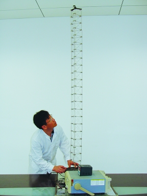 這是伸展開(kāi)的衛星太陽(yáng)能電池用盤(pán)壓伸桿，20厘米長(cháng)螺旋狀的盤(pán)壓伸桿（右側小圖）打開(kāi)后能達2米長(cháng)（8月7日攝）。（新華社發(fā)）